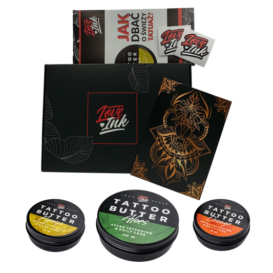 A collection of Love Ink tattoo care products displayed on a transparent background. The items include a black box with the Love Ink logo, a brochure on how to care for a new tattoo, a sticker, a black and gold tattoo design, and three tins of Tattoo Butter in different formulations for daily care.