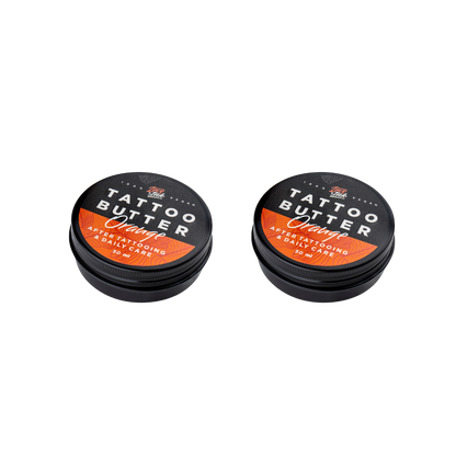 Two tins of Love Ink Tattoo Butter Orange on a transparent background. Both tins are labeled 'Tattoo Butter Orange' for after tattooing and daily care, and each contains 50 ml.